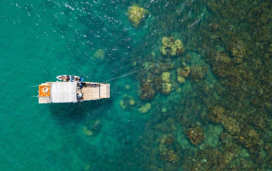 a drone shot of a small boat over a reef